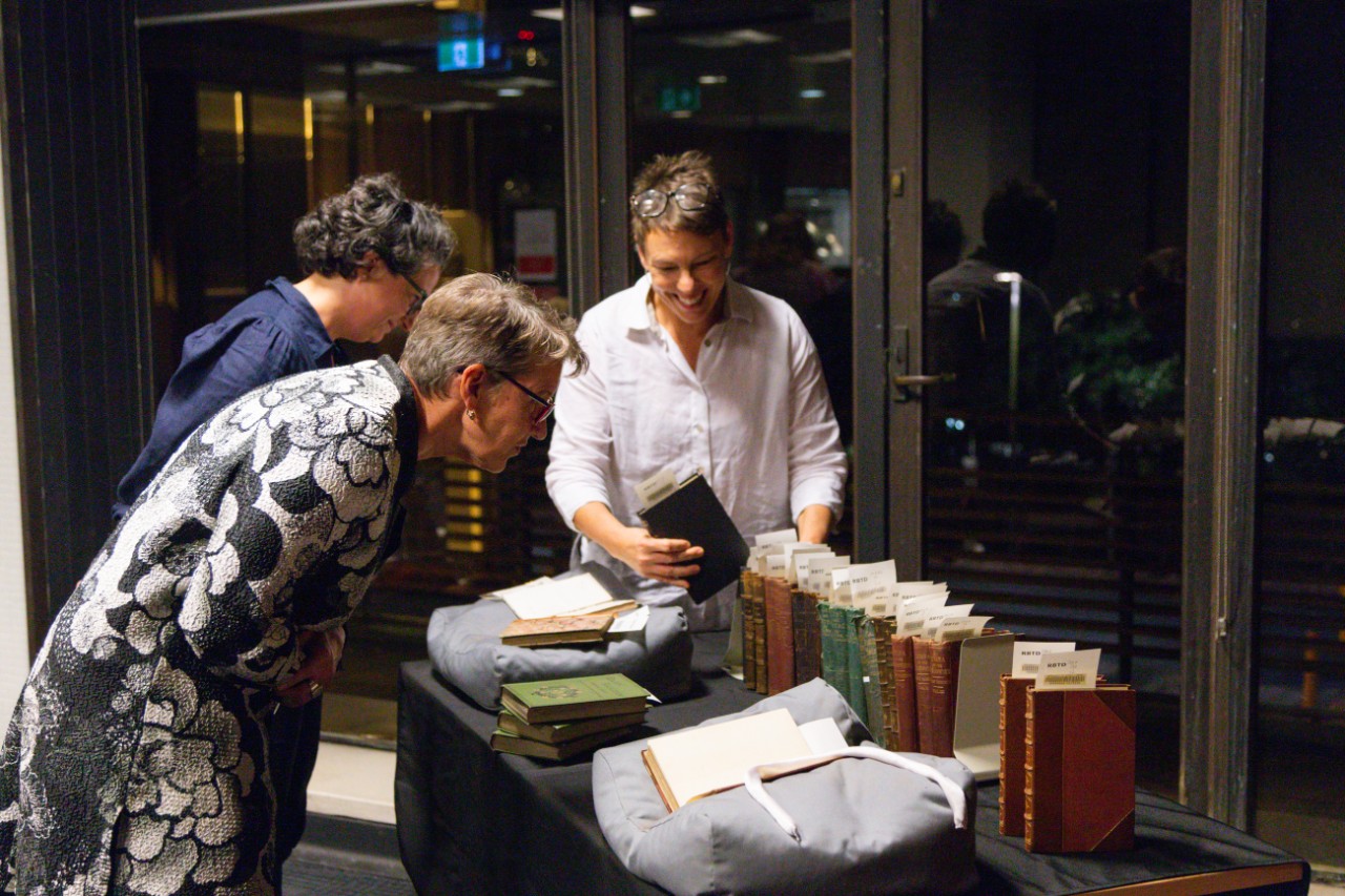People viewing rare books displayed on a table
