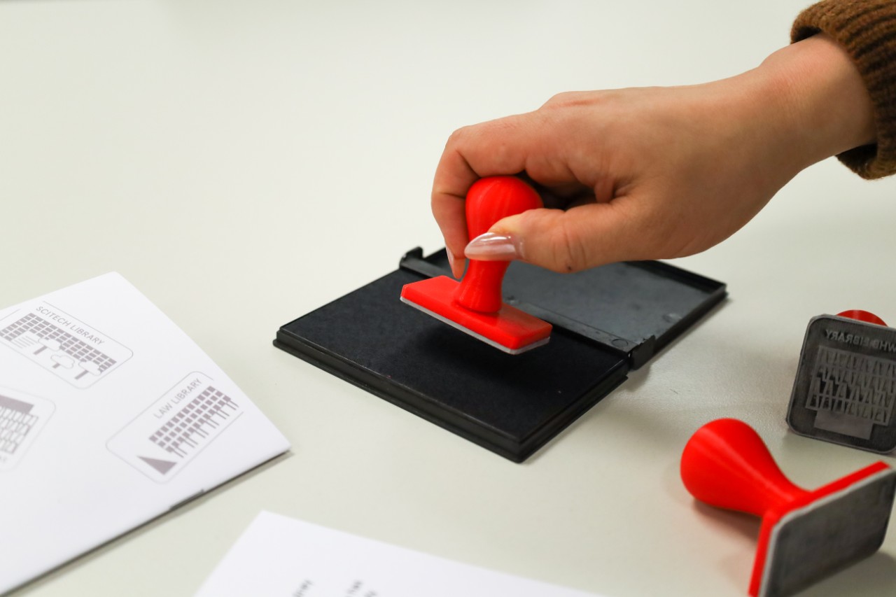 A person holding a stamp with ink pressed onto it