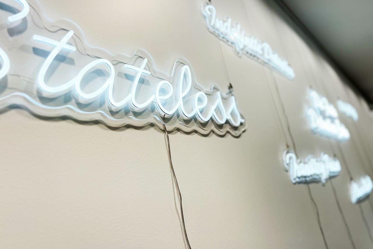 A close up shot of a series of white neon signs, with a focus on the word Stateless
