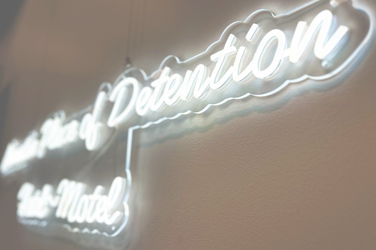 A close up shot of a series of white neon signs, with a focus on the word Detention
