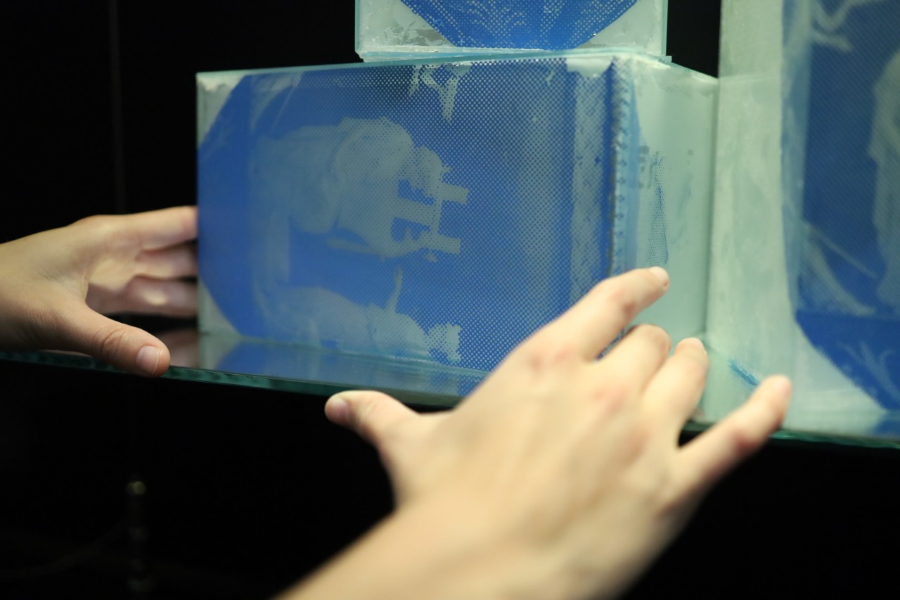 hands touching glass artwork