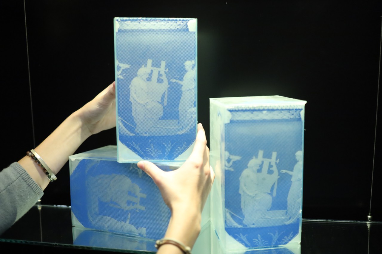 hands touching glass artwork