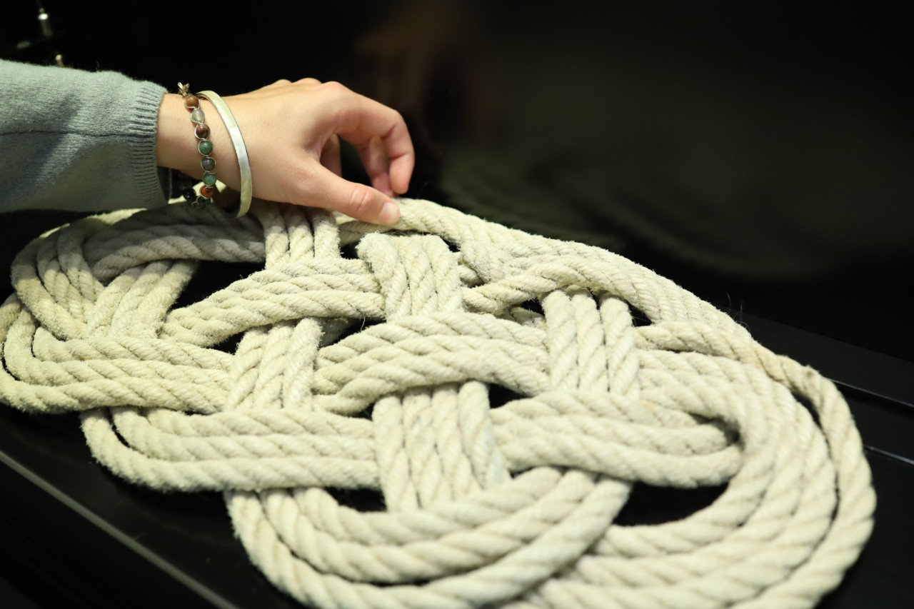 hands touching rope artwork