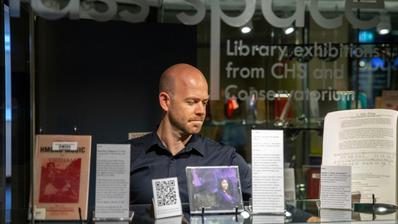 Dr Steve Barry installing the 'Dzô! SCM Jazz in Vietnam, 2022 & 2023 exhibition' at the Conservatorium of Music Library