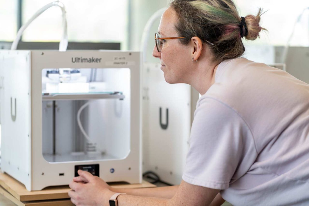 A female student standing in front of a 3D printer