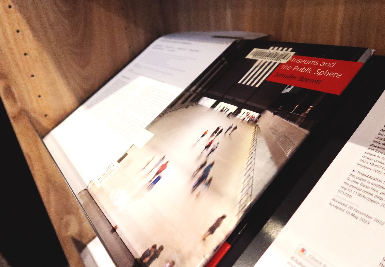 An angle shot of a book cover, of people walking in a public space in a blurry setting