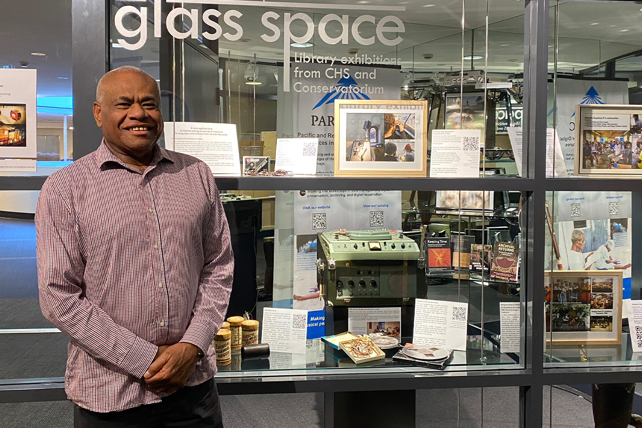 A man standing in front of glass shelves of an exhibition