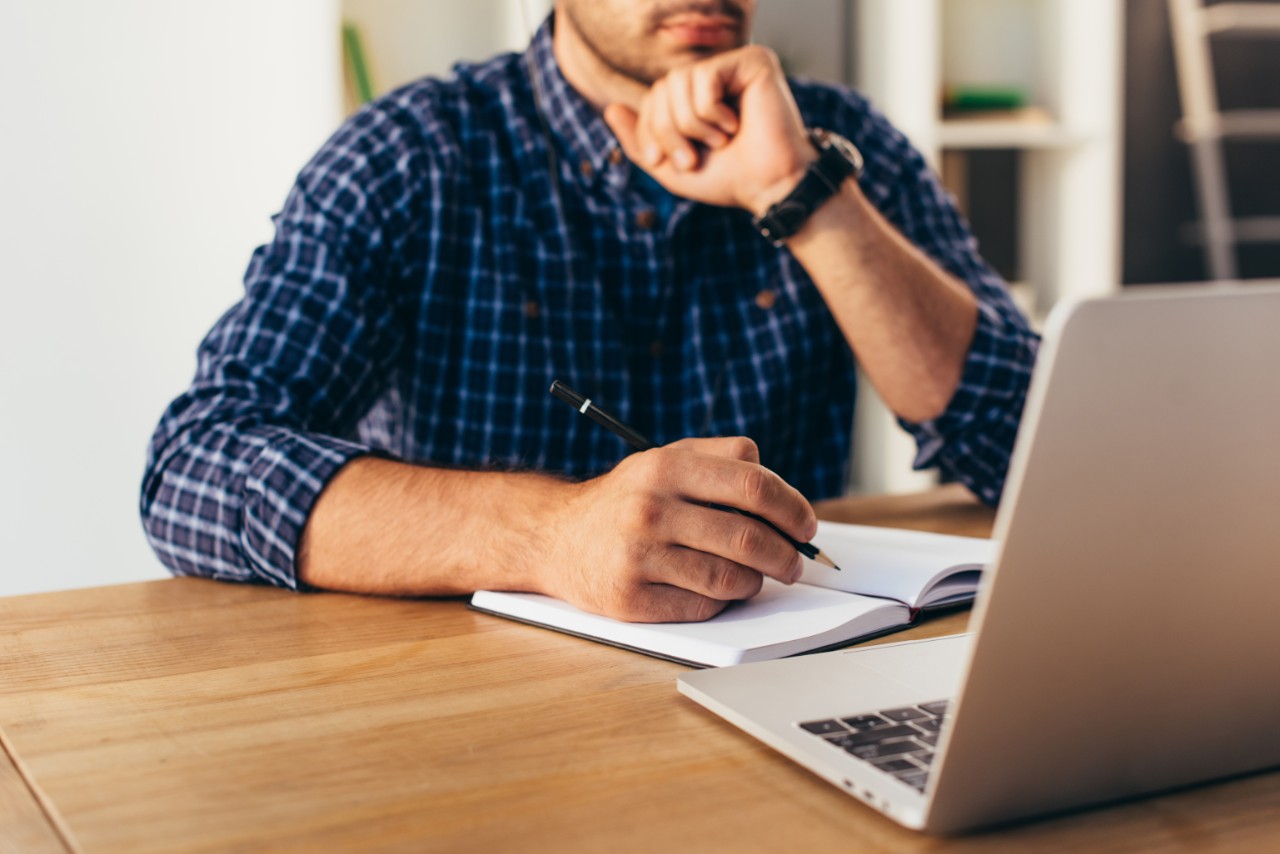 cropped shot of businessman with notebook taking part in webinar in office