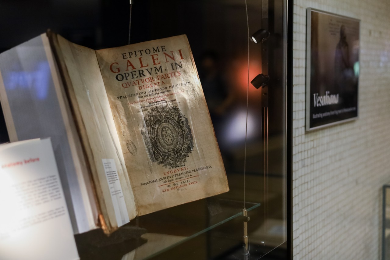 Close up of an open book, Epitome galeni operum, on display in a glass cabinet.