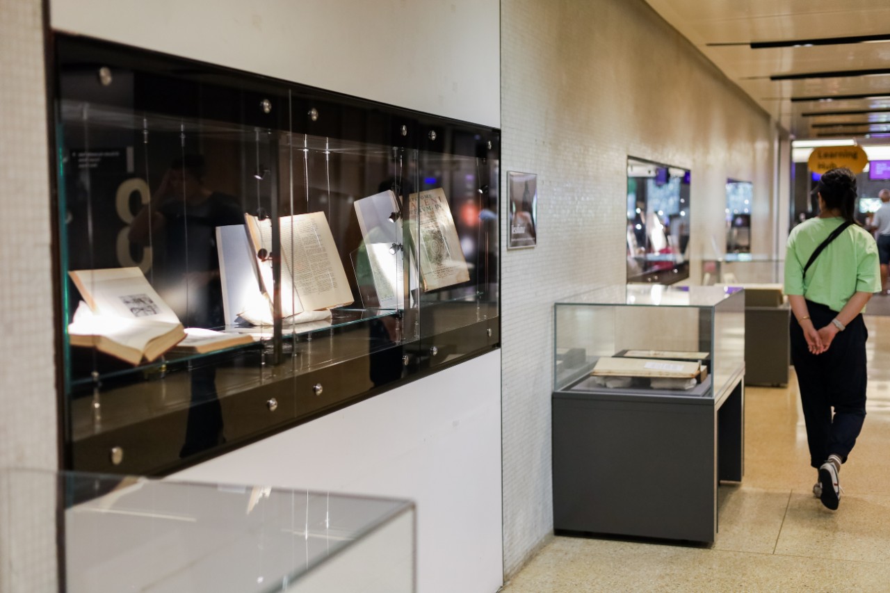 Person walking past a display of books in glass cabinets