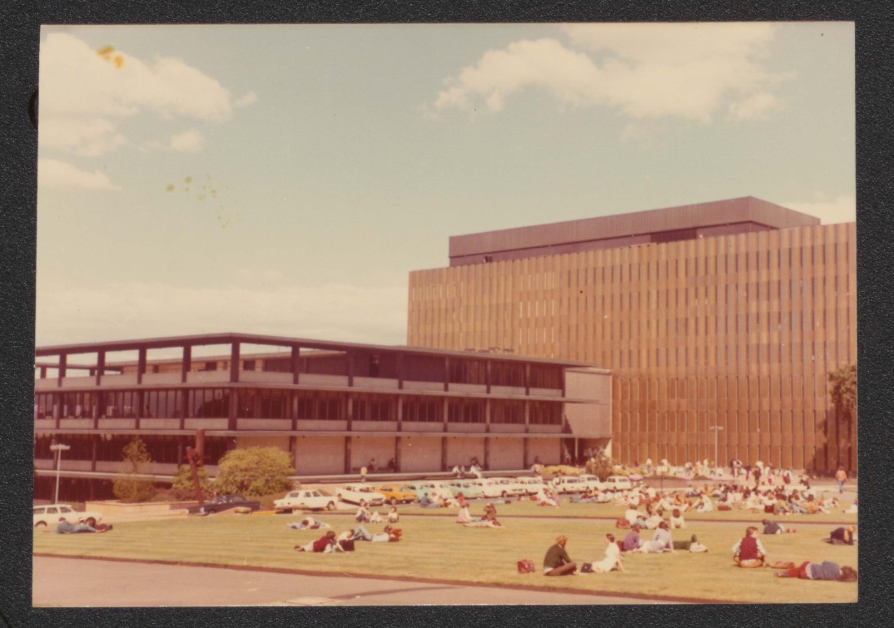 An image of Fisher Library taken from outside the Quadrangle. Students are sitting on the lawns.