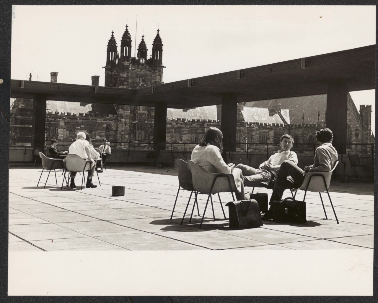 A black and white image of two groups of people sitting on the rooftop terrace in the 1960s