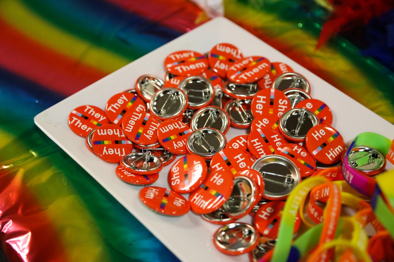 Pronoun badges and pride bracelets on a white platter
