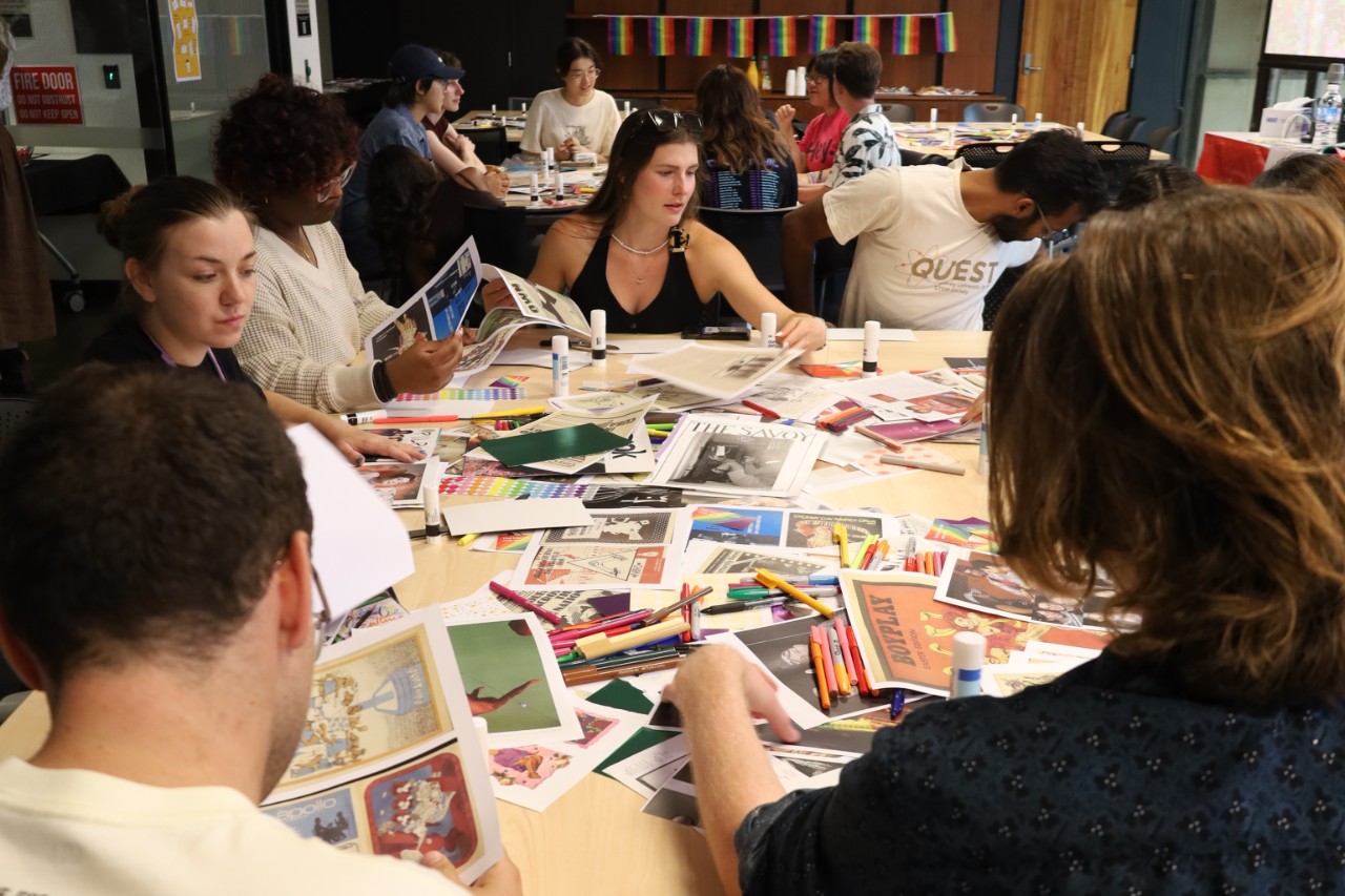 A colour photograph showing a group of young people crafting around a table scattered with collage materials