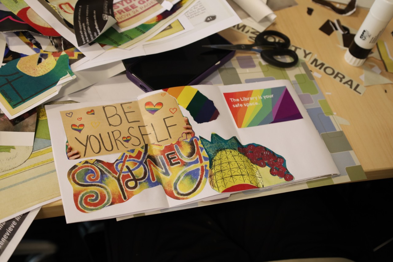 A spread from a handmade zine featuring a collage of materials. Rainbow text reads "Be yourself sydney" and "The library is your safe space"